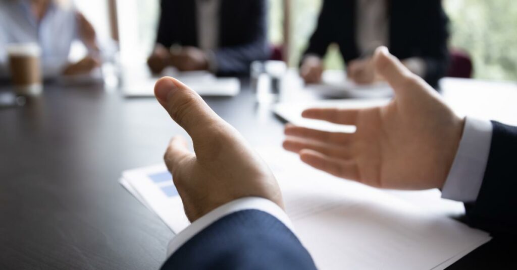 A business coach speaking at a table to others about the qualities of a good business coach